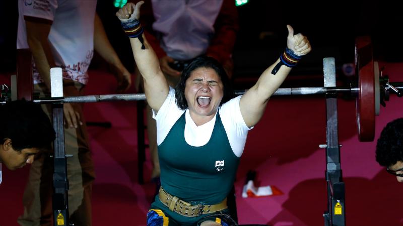 a female powerlifter celebrates on the bench