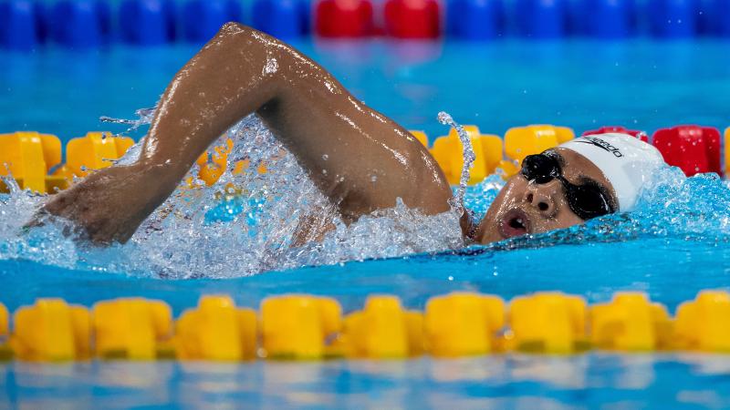 a female Para swimmer doing freestyle and taking a breath