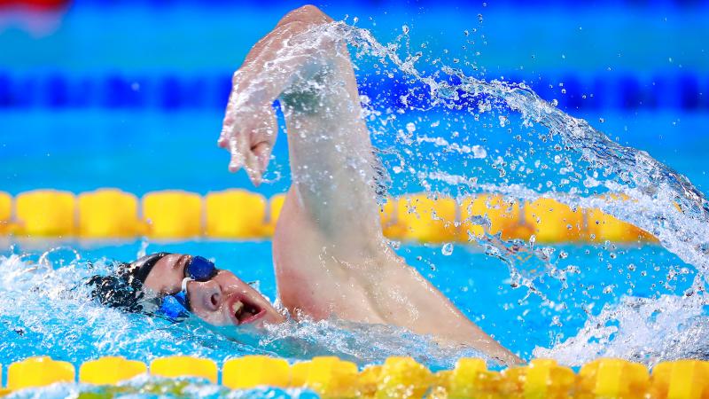 a male Para swimmer mid-backstroke