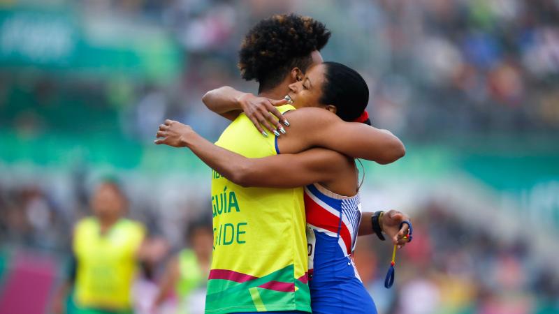 a female vision impaired runner hugs her guide