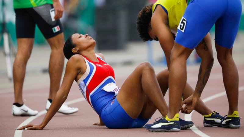 a female vision impaired runner lying on the track having her leg massaged