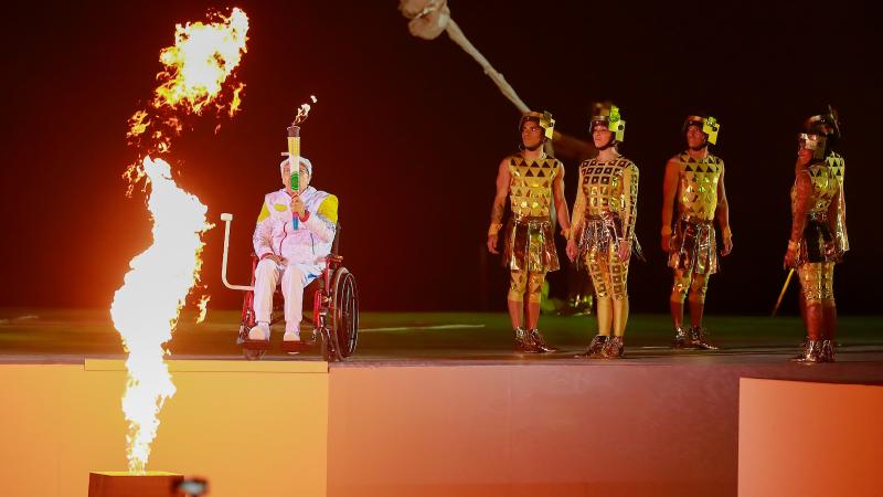 a male wheelchair athlete holding a lighted torch