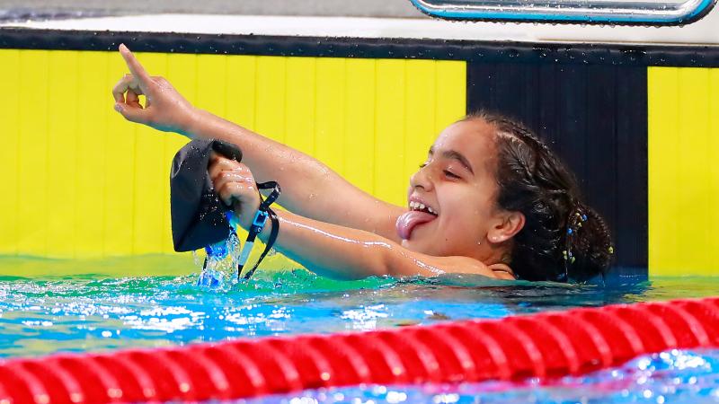 a female Para swimmer in the pool sticks her tongue out