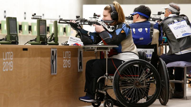 a female Para shooter in a wheelchair fires a rifle at the target