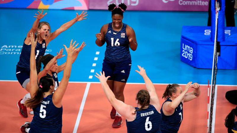 female sitting volleyball players celebrating on the court