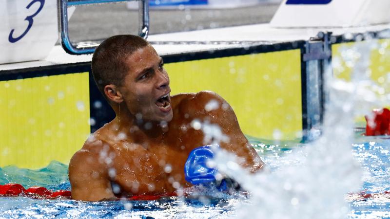 a male Para swimmer cheers in the water