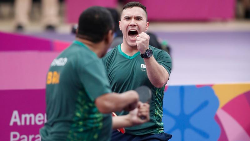 two male table tennis players celebrate winning a point