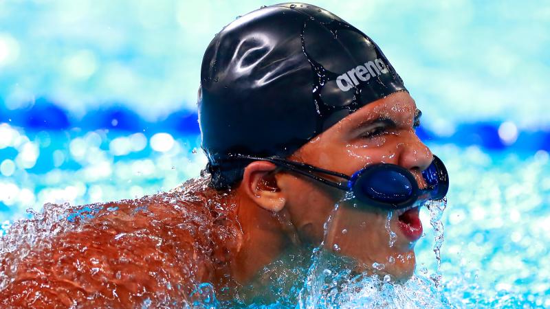 a male Para swimmer in the water with his goggles on his head