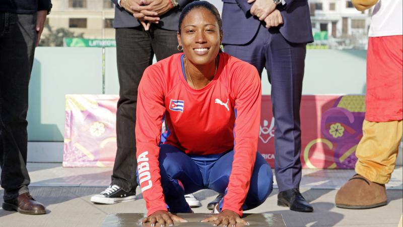 a female Para athlete places her hands in cement to leave prints