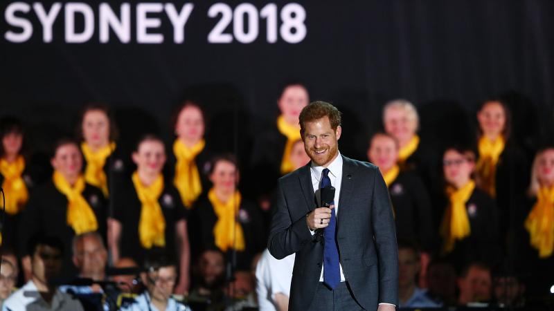 a man speaking on a stage in a suit with a microphone