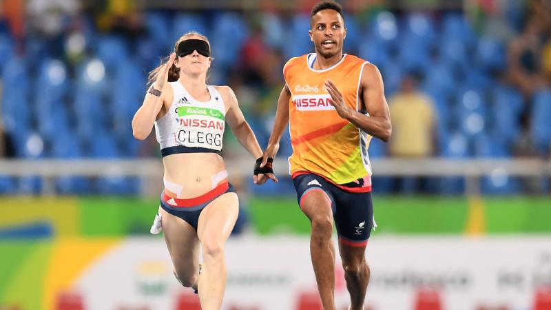 a female vision impaired runner and her guide sprint for the line