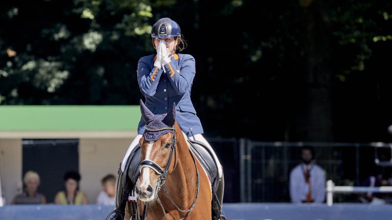 Woman on her horse claps hands in amazement