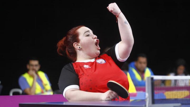 a female wheelchair table tennis player punches the air in victory