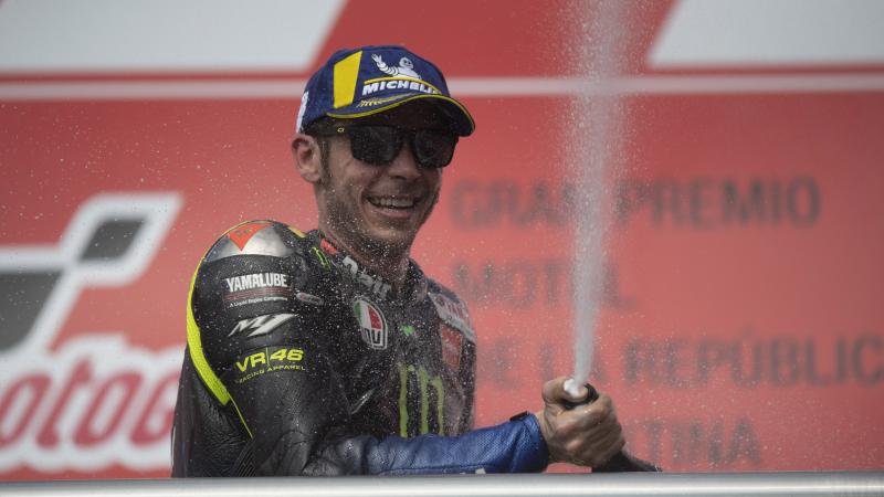 a male motorcycle rider spraying champagne on the podium