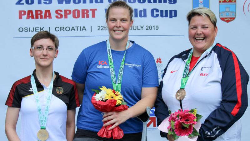 Three female shooting Para sport athletes podium winners pose