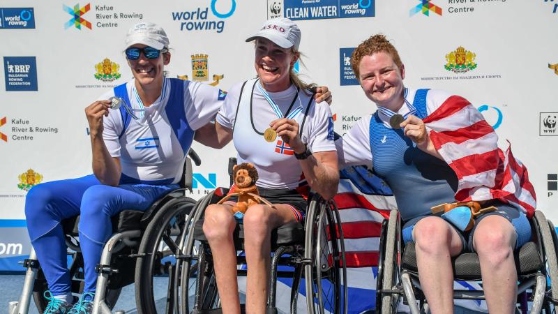 Three female rowers in wheelchairs pose with their medals