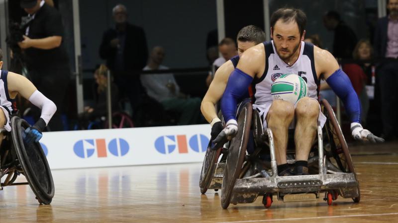 Man in wheelchair has rugby ball on lap