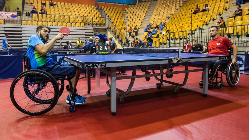 Two men in wheelchairs play table tennis