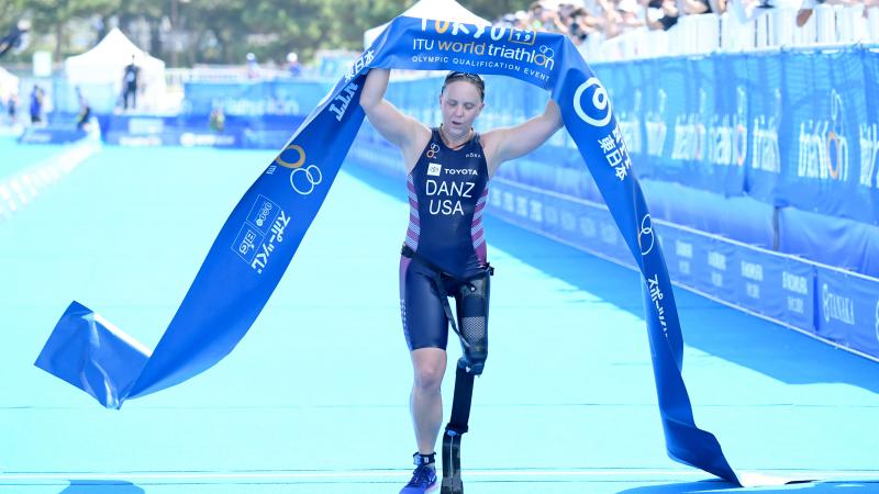 US female triathlete with left leg prosthesis crosses finish line