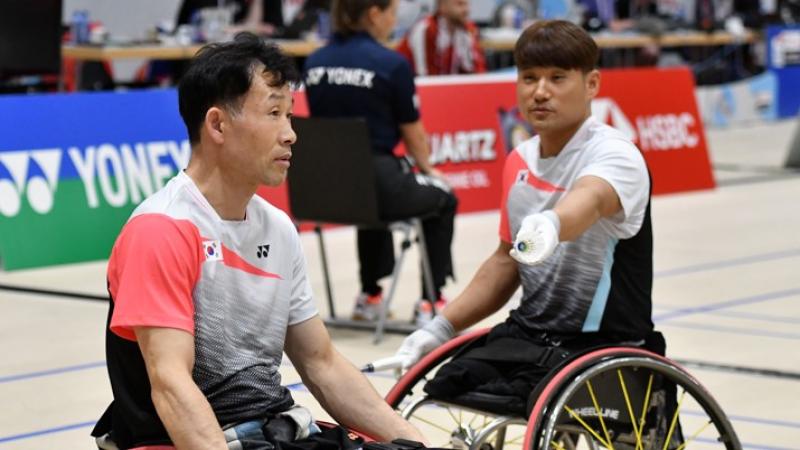 Korean badminton player in wheelchair hands his teammate the birdie