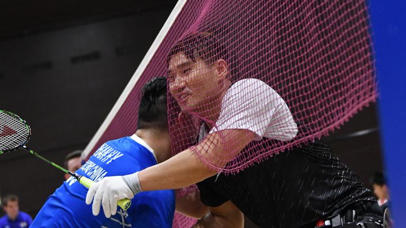 Two male wheelchair badminton players hug each other