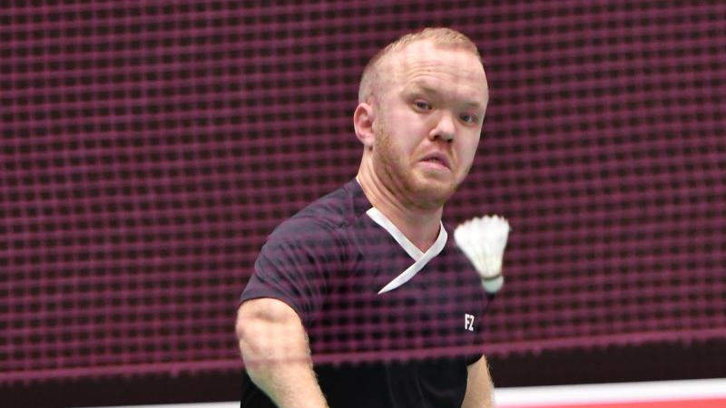 Short statured British badminton player lunges for the birdie