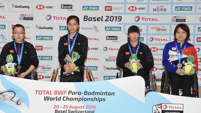 Four female badminton players in wheelchairs pose on podium