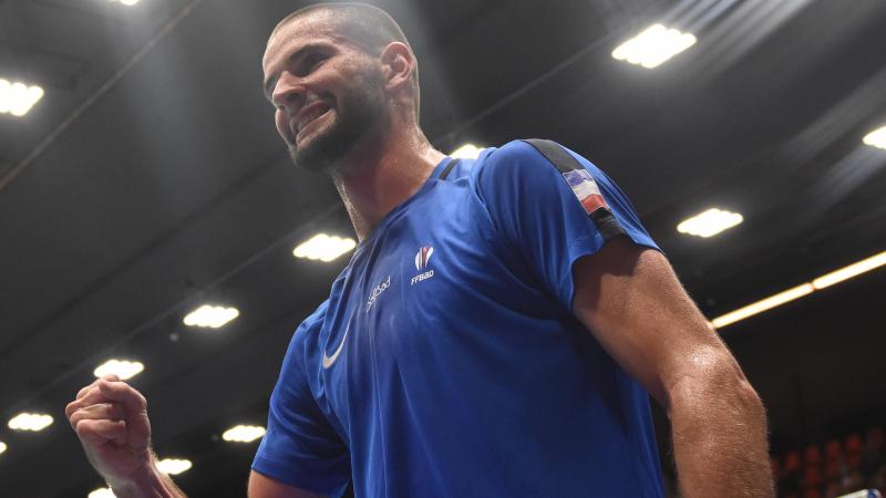 French male badminton player clutches fist smiling