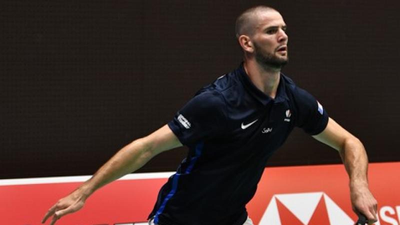 French male badminton player about to lunge for the birdie