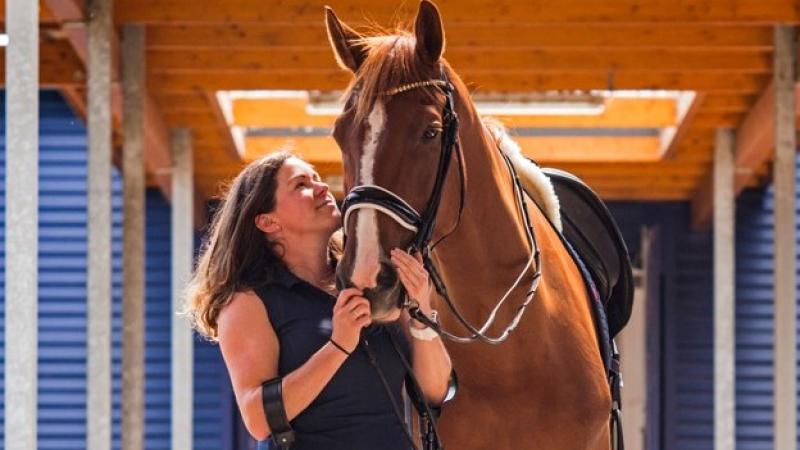 A female Para equestrian rider on crutches holds the bridle of her horse