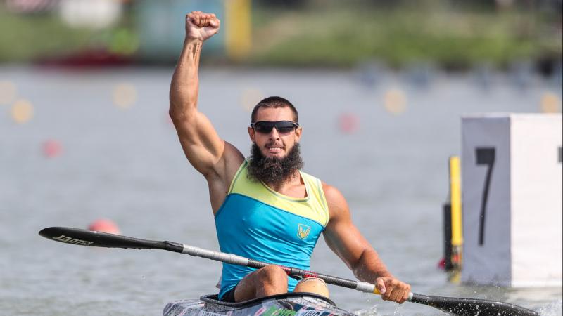 Man in kayak raises fist in air to celebrate
