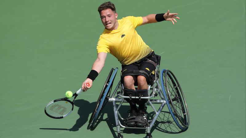 a male wheelchair tennis player hits a forehand