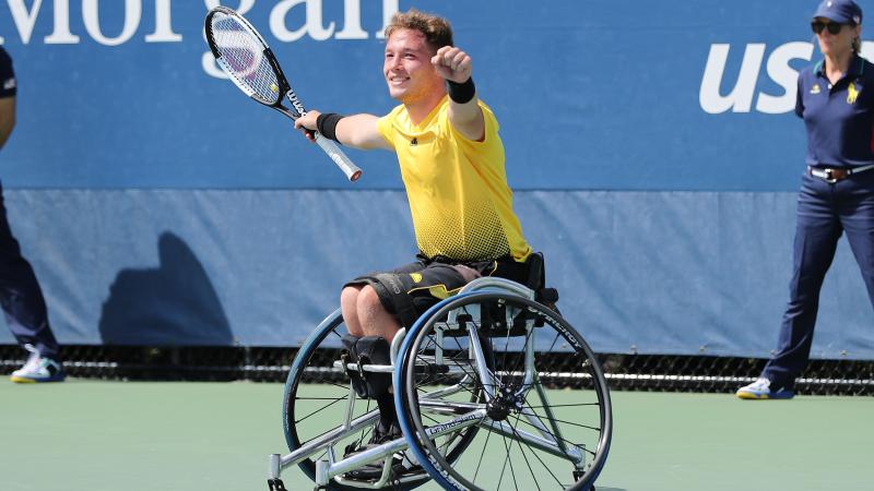 a male wheelchair tennis player celebrates on the court