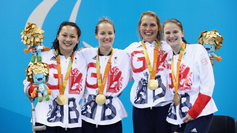 four female Para swimmers on the podium holding their gold medals 