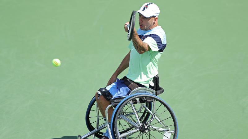 a male wheelchair tennis player hits a forehand