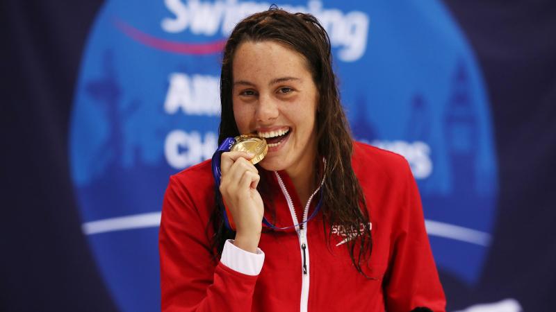 a female Para swimmer biting her gold medal