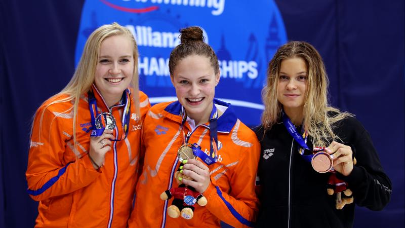 three female Para swimmers on the podium holding up their medals