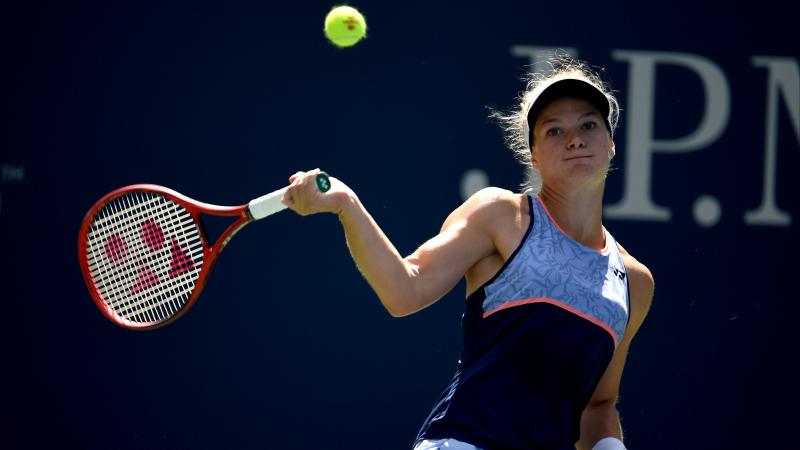 a female wheelchair tennis player hits a forehand