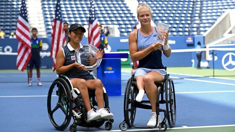 two female wheelchair tennis players holding up trophies