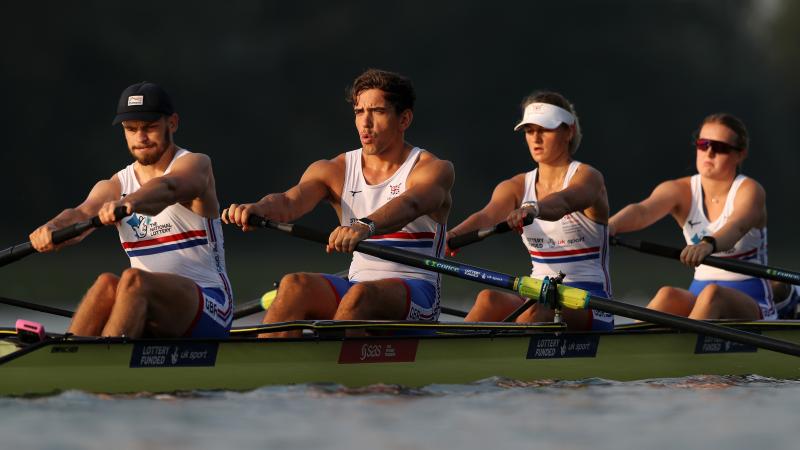 Mixed coxed four rowing crew rowing on the water