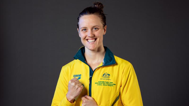 A woman wearing Australia's tracksuit smiling to camera