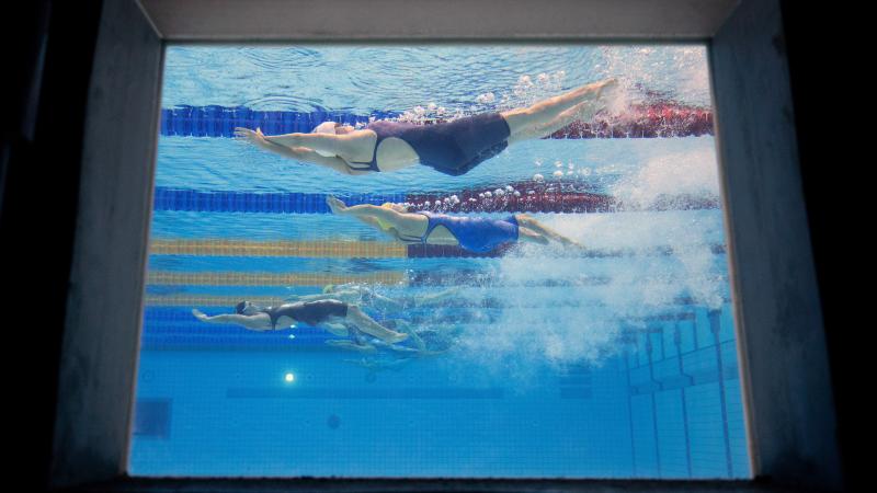 An underwater image of female Para athletes swimming backstroke