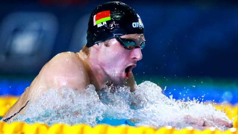 a male Para swimmer takes a breath during a breaststroke