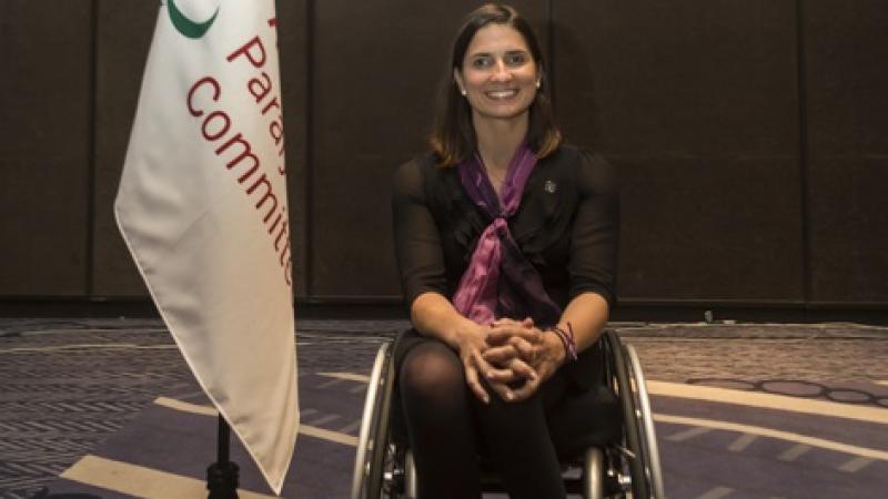 a female wheelchair athlete next to a flag