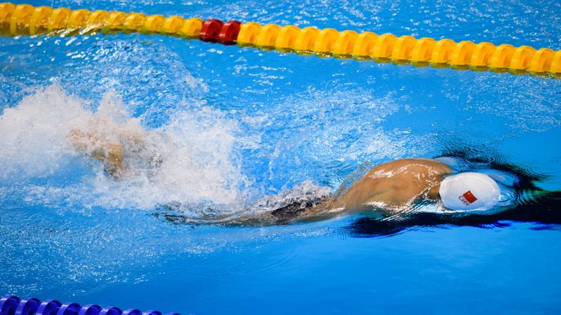 a male Para swimmer with no arms does breaststroke in the water