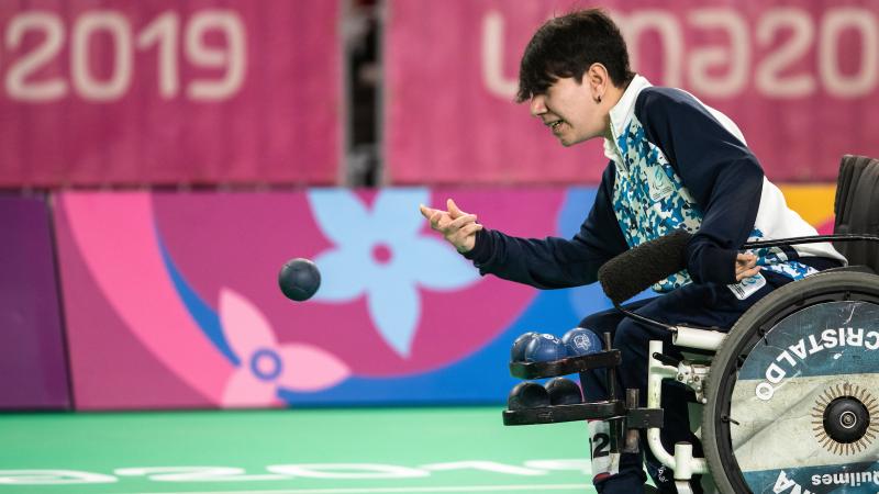 a male boccia player throws a ball