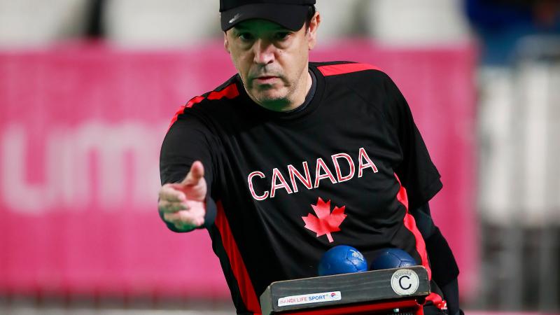 a male boccia player throws a ball