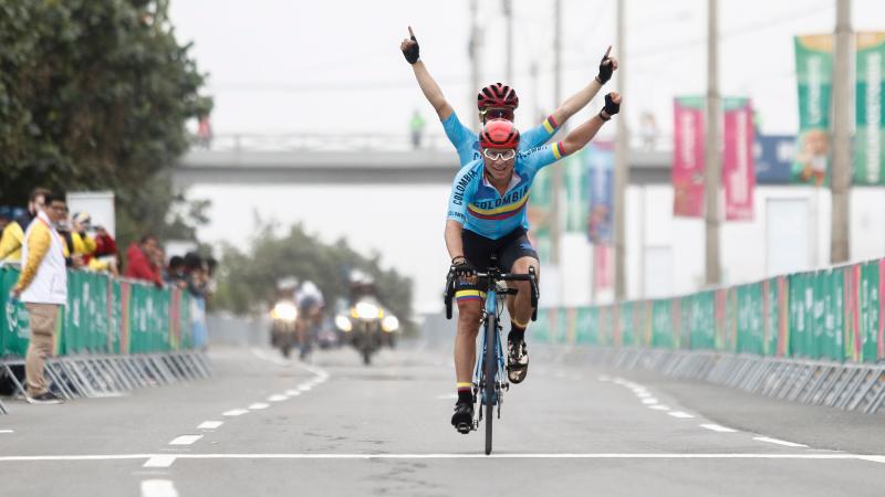 a male vision impaired cyclist and his guide ride a tandem across the finish line and celebrate