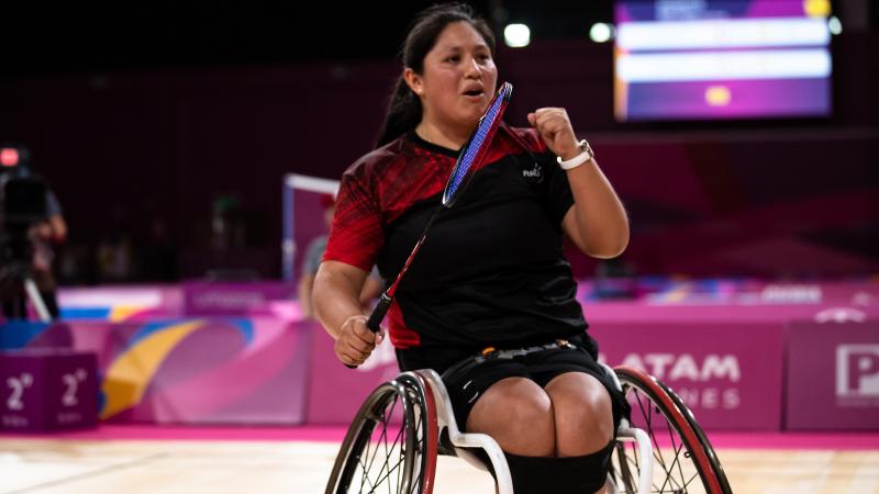 a female wheelchair badminton player pumps her fist after a point