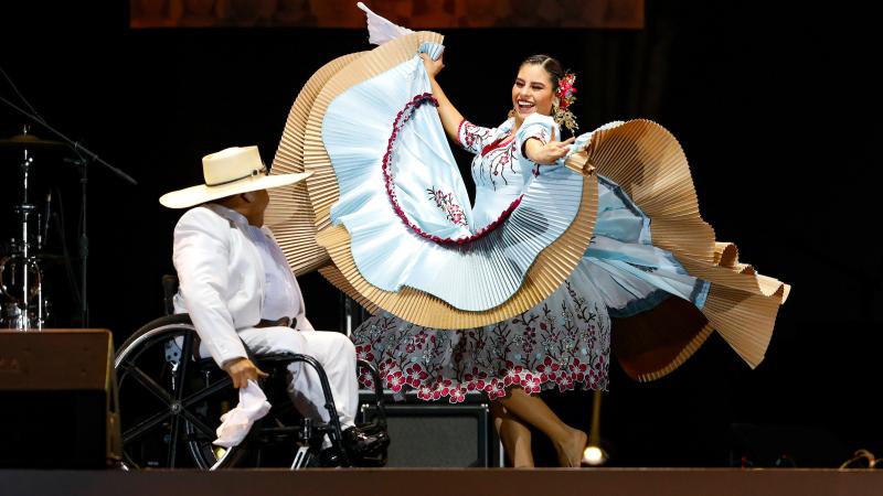 a female dancer swirls a giant skirt on a stage